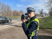 policjant stojący z urządzeniem do mierzenia prędkości