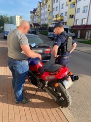 policjant stojący z mężczyzną przy motocyklu widziani od tyłu